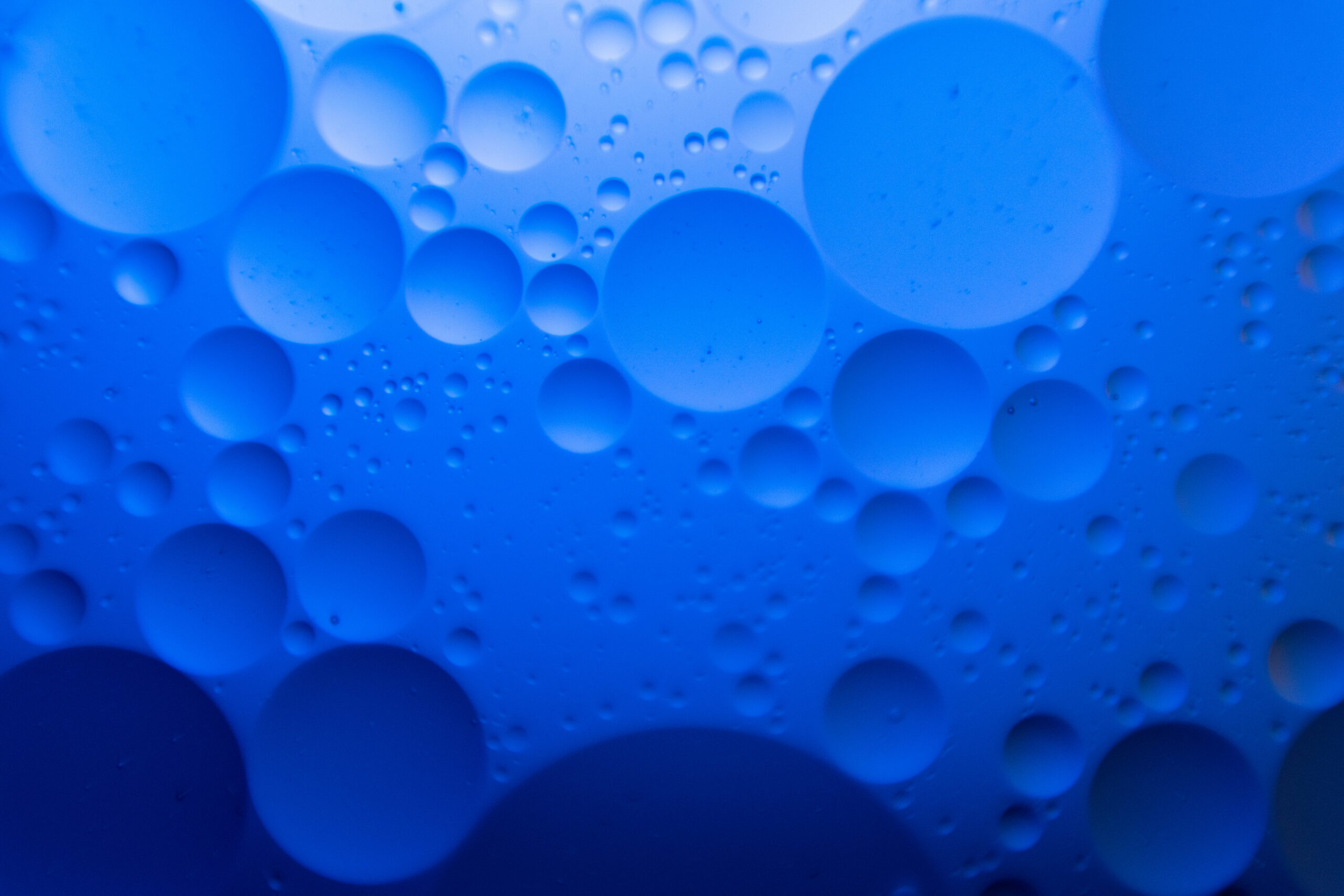 Numerous translucent blue bubbles of various sizes cluster together against a blue background.