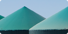 Three large, green, cone-shaped structures are shown against a clear blue sky.