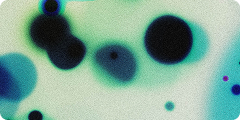Abstract image showing large and small dark circular shapes on a greenish-blue background, with a grainy texture.